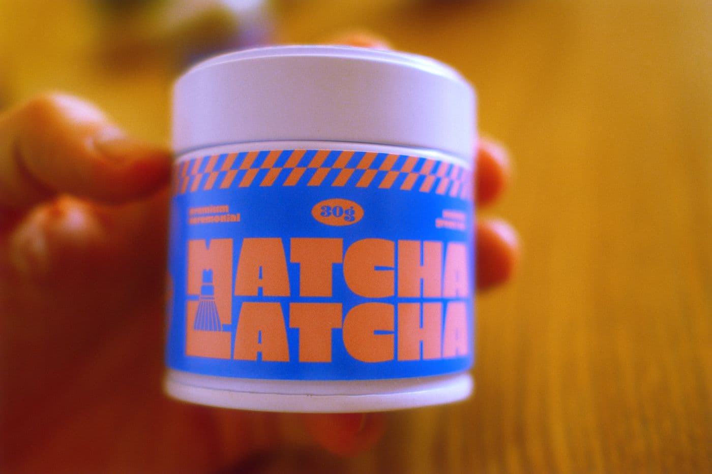 Matcha Latcha Dose in einer Hand bei Sonnenuntergang