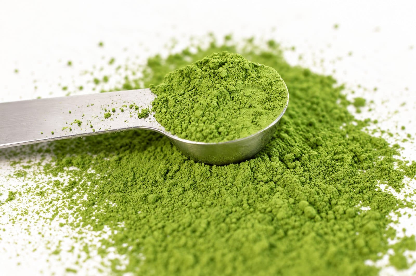 Messlöffel in frisch gemahlenem, leuchtend grünem Matcha-Pulver